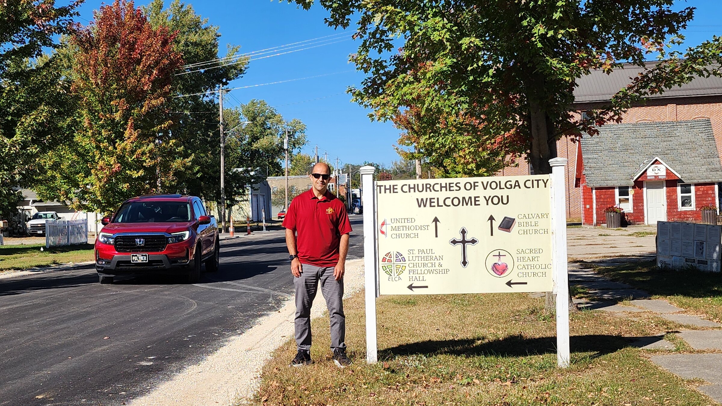 Eric Cochran beside a Volga City sign with the newly paved Washington Street visible behind him.