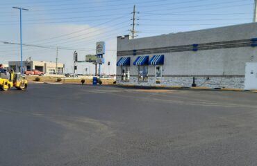 Roller compacting the newly paved asphalt surface beside a commercial building in St. Peters, Missouri.